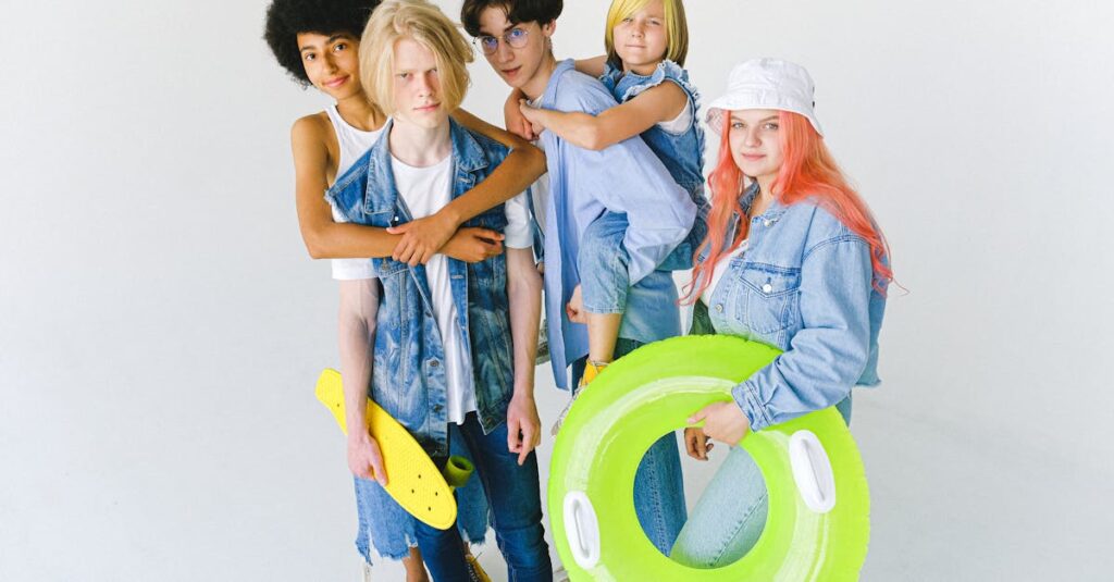 High angle of cool multiracial friends in casual clothes standing in studio with inflatable ring and longboard while giving piggyback ride and hugging while looking at camera on white background