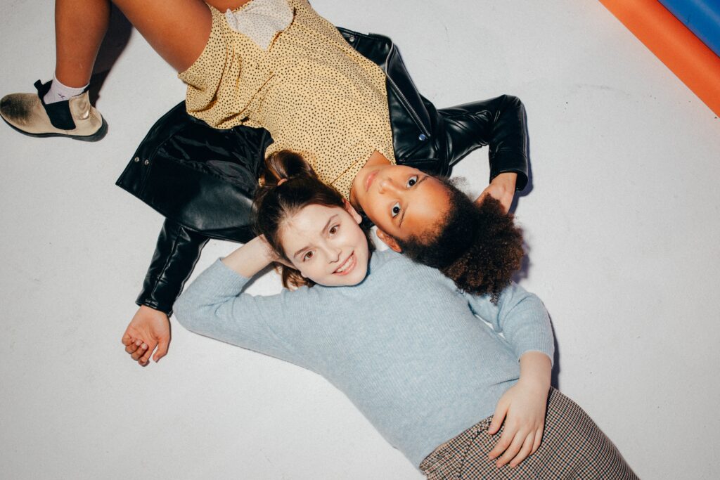Two girls lying on the floor, embodying fun and friendship, with joyful expressions.