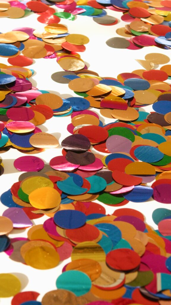A vibrant close-up of colorful confetti scattered on a white surface, perfect for celebrations.