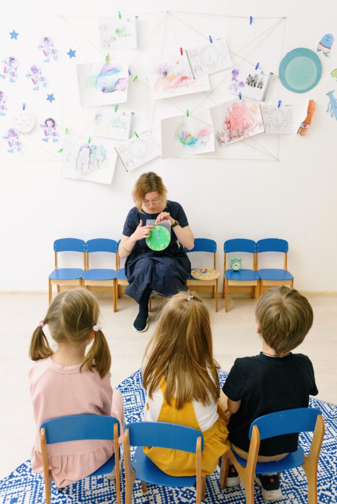Teacher engages children during storytime in a colorful preschool classroom.